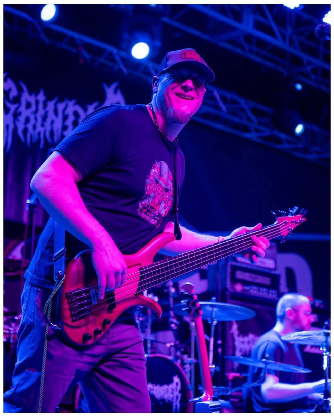 Penumbra bassist performing live on stage under blue and magenta lights